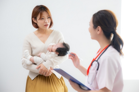 医師と会話をする赤ちゃんを抱いた女性