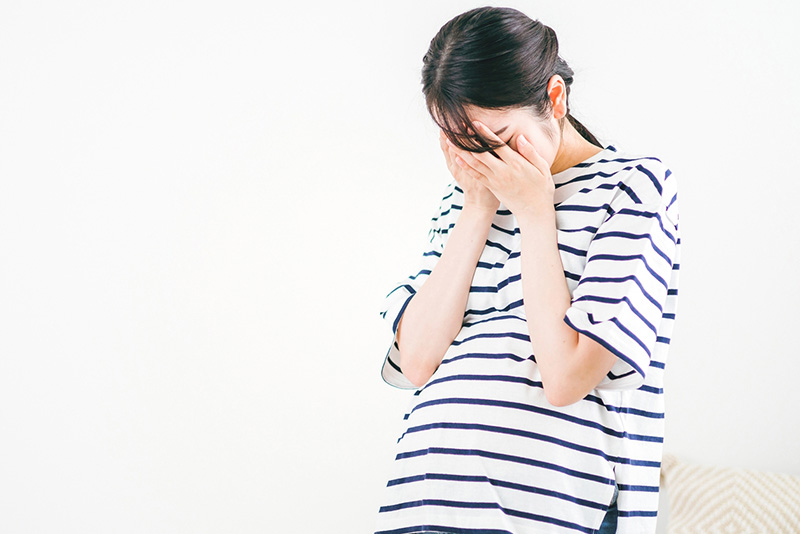 悩んで顔を手で覆う女性